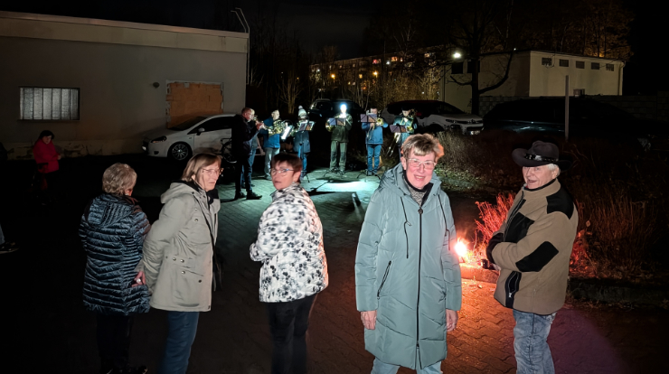 Mehrere Personen hören dem Posaunenchor zu.